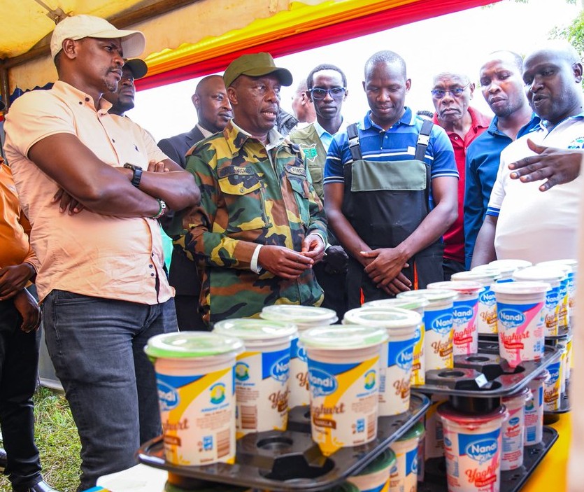 Chief Conservator of Forests Alex Lemarkoko (center, in camouflage uniform) examines community-produced dairy items at the Kaimosi Agricultural Expo 2026 in Emgwen, Nandi County, Kenya.    /Photo credit, KFS