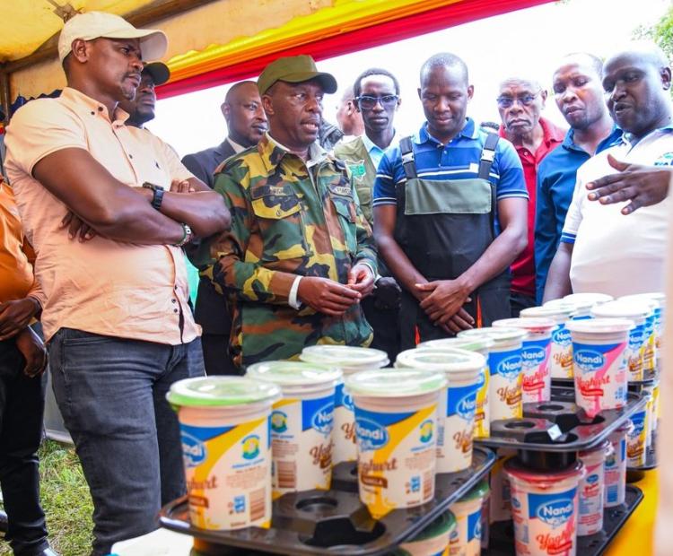 Chief Conservator of Forests Alex Lemarkoko (center, in camouflage uniform) examines community-produced dairy items at the Kaimosi Agricultural Expo 2026 in Emgwen, Nandi County, Kenya.    /Photo credit, KFS